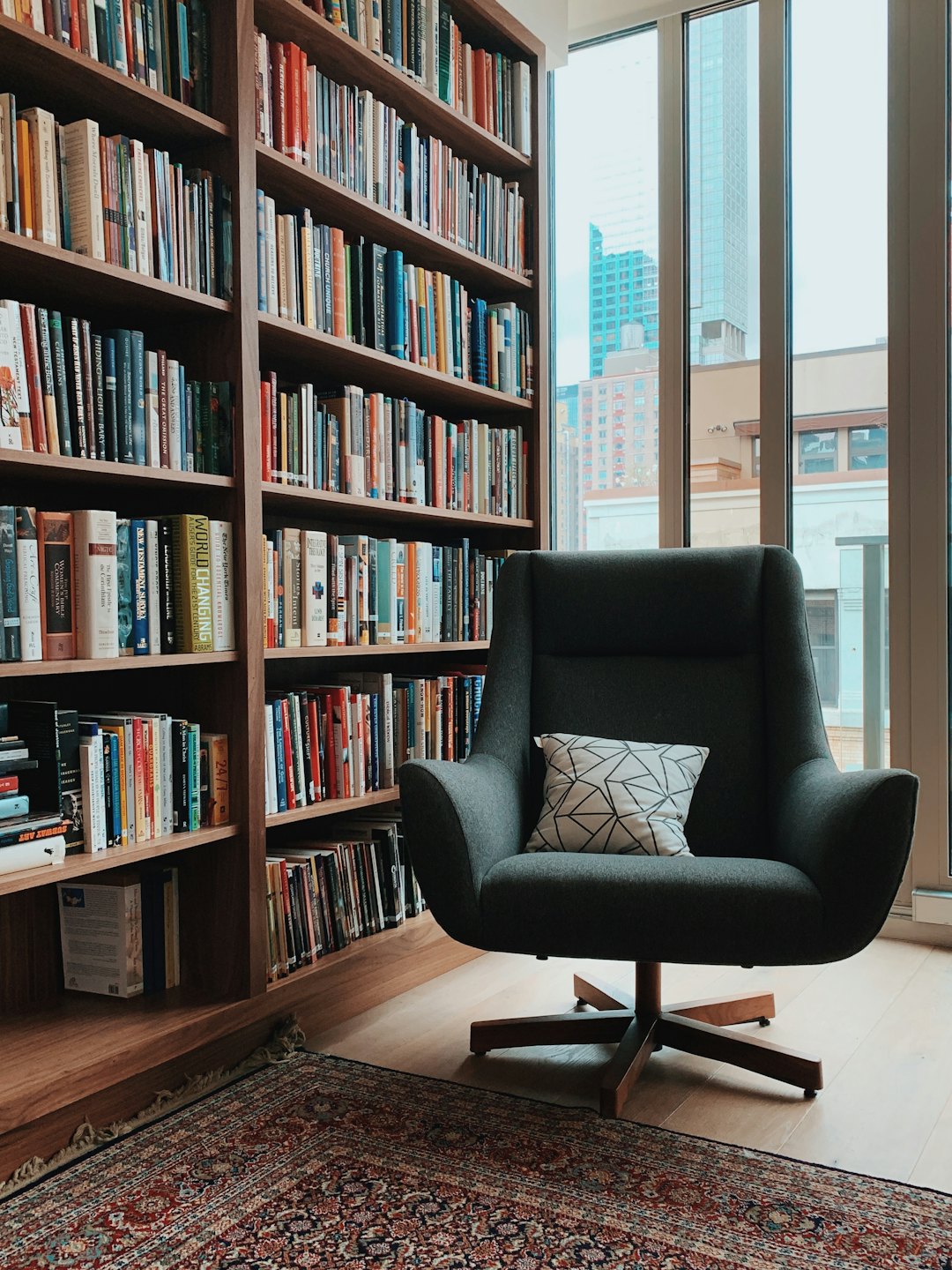 Cozy reading nook with armchair and city view.
